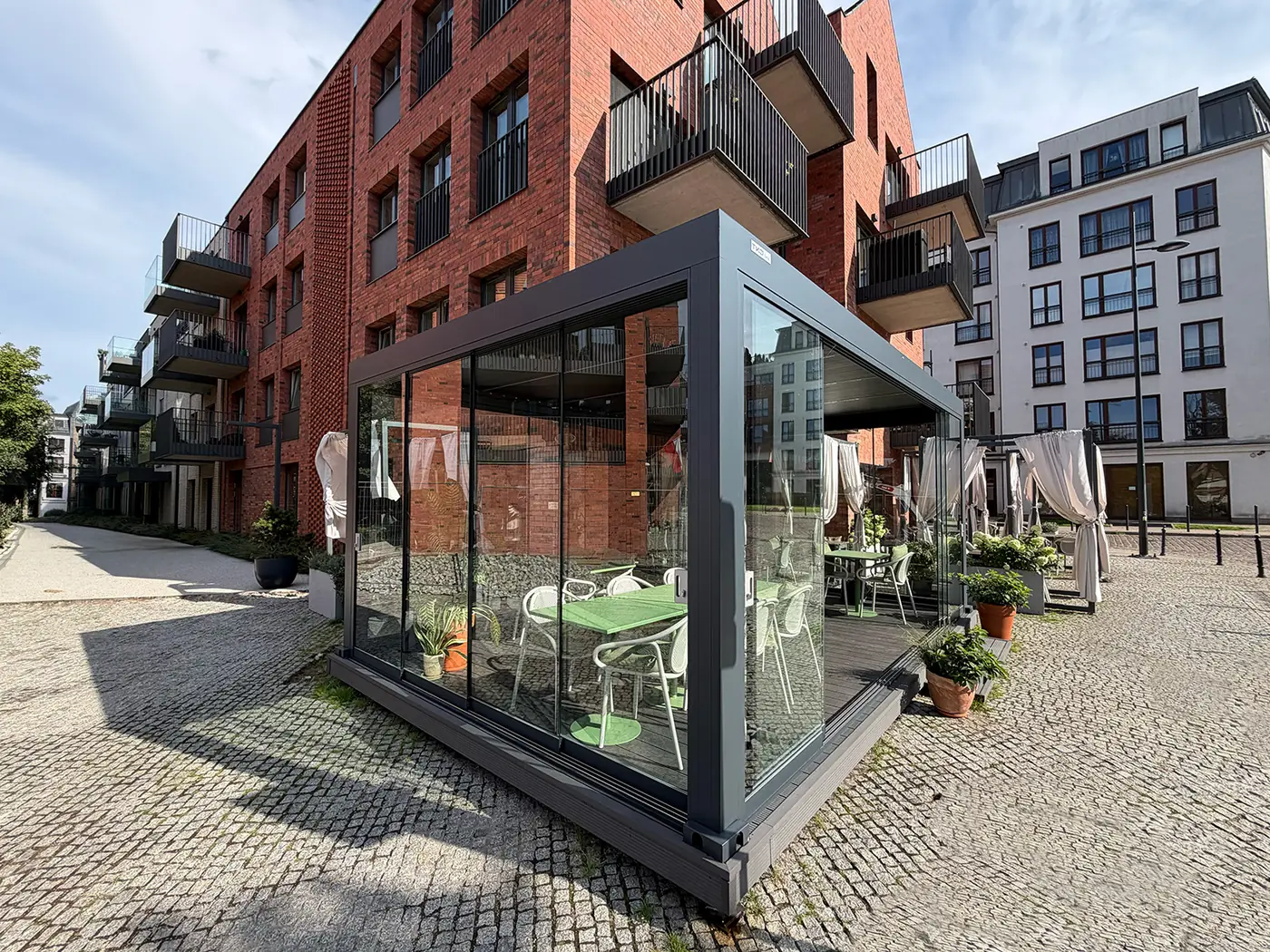 Pergola gastronomiczna 6×4 m w Gdańsku widziana od ulicy - szklane drzwi przesuwne i podest kompozytowy