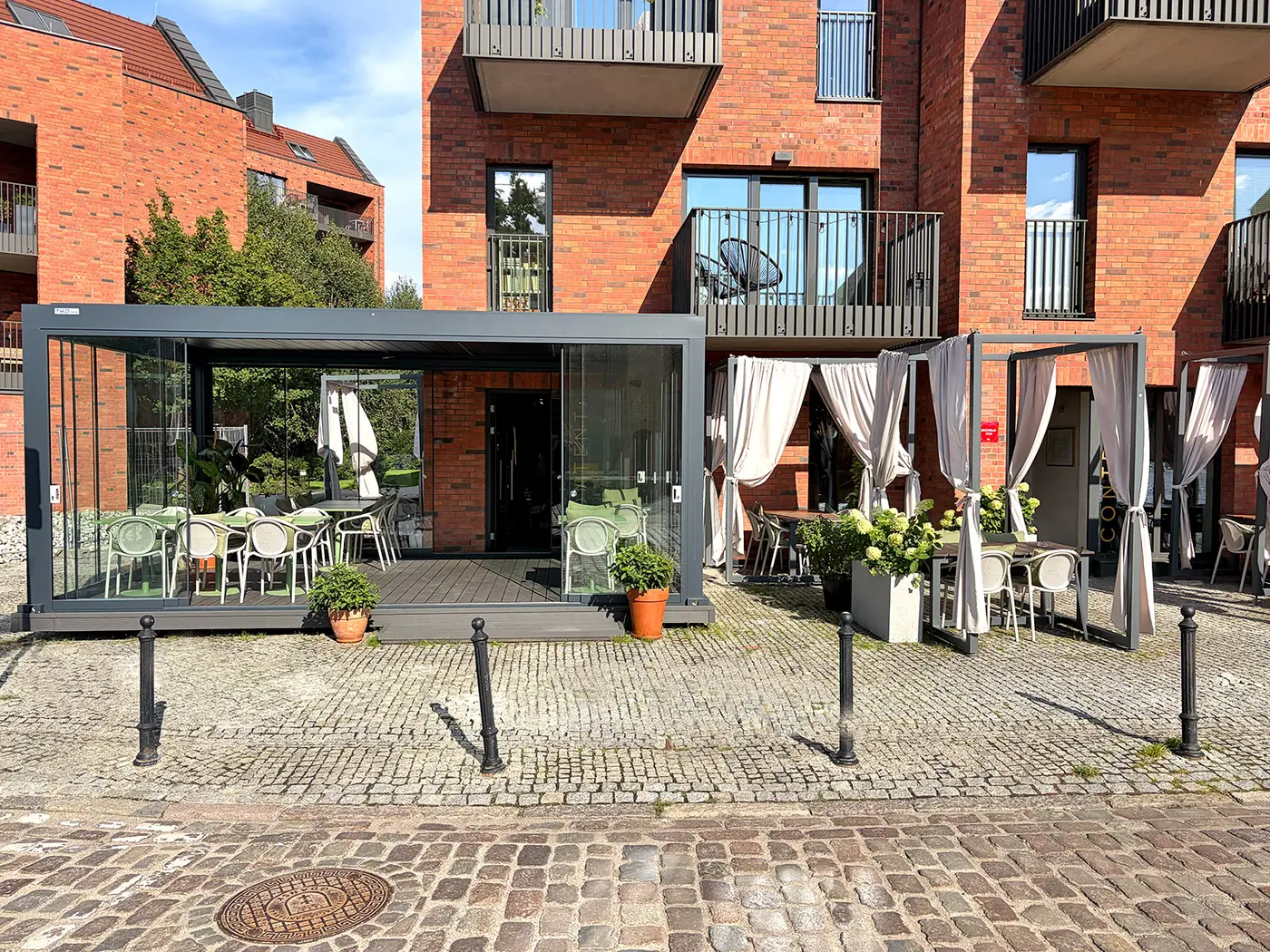 Zadaszenie ogródka restauracyjnego w Gdańsku przy budynku z czerwonej cegły - pergola aluminiowa z zasłonami