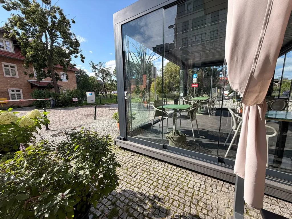 Szklana zabudowa pergoli restauracyjnej w Gdańsku - bezramowe drzwi przesuwne od strony ogrodu