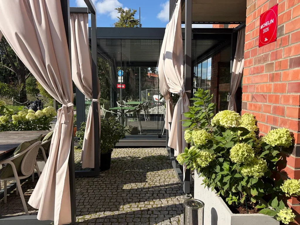 Wejście do pergoli restauracyjnej w Gdańsku - zasłony i donice przy szklanej ścianie