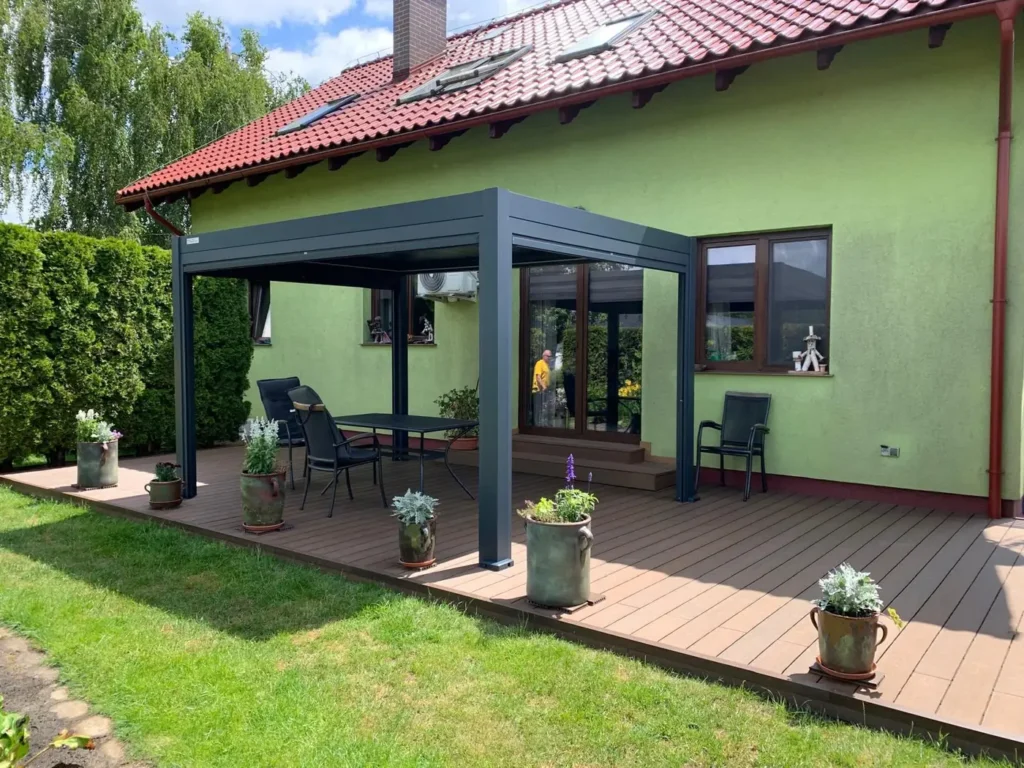 Pergola sterowana manualnie BASE 4×3 w Klamrach - konstrukcja przyścienna nad tarasem kompozytowym